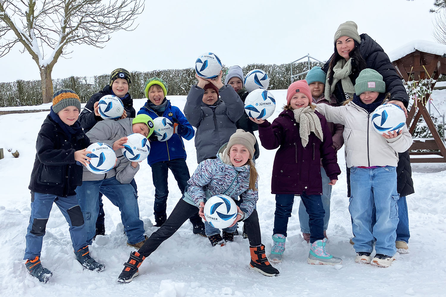 Grundschulkinder und der Hortleiterin freuen sich über die Jüttner-Fußbälle